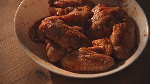 Raw marinated chicken wings in bowl on wooden surface close-up Stock Footage 312647852