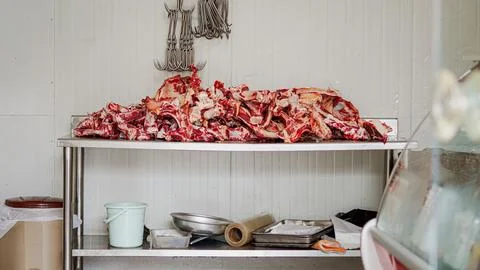 Raw meat and bones piled on a stainless steel table in a butcher shop. Stock Photos