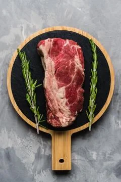 Raw meat beef on a cutting board with rosemary and spices. Top view, flat lay Stock-Fotos