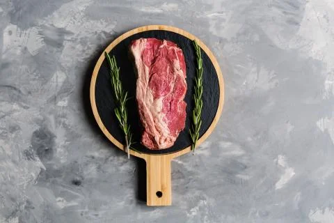 Raw meat beef on a cutting board with rosemary and spices. Top view, flat lay Foto stock