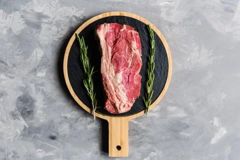 Raw meat beef on a cutting board with rosemary and spices. Top view, flat lay Stock Photos