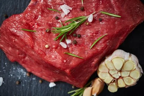 Raw meat beef steaks on black slate board with spices, garlic and rosemary over Stock Photos