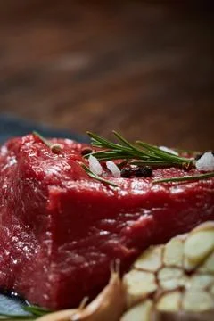 Raw meat beef steaks on black slate board with spices, garlic and rosemary over Stock Photos