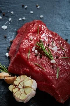 Raw meat beef steaks on black slate board with spices, garlic and rosemary over Stockfoto's