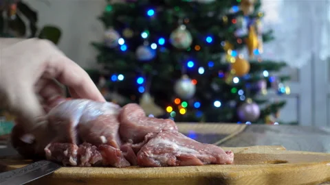 Raw meat on a chopping board in front of a Christmas tree in 4K. Stock Footage 130875519