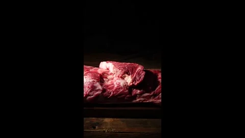 Raw Meat Chunks Falling onto Wooden Board against Black Background 4K Stock Footage 334909327