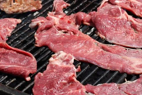 Raw meat cooking on a grill Stock Photos