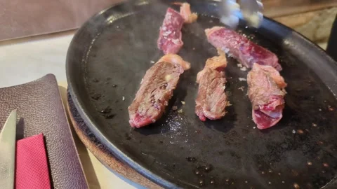Raw meat cooking on a hot plate at a restaurant table Stock Footage 306242517