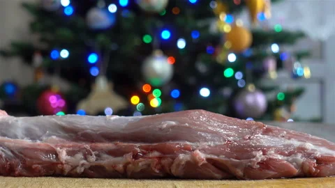 Raw meat on a cutting board in front of the Christmas tree. Stock Footage 134594213