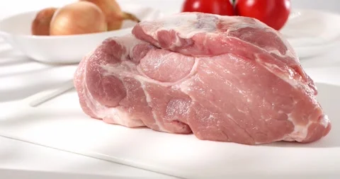 Raw meat at the cutting board. piece of fresh pork on the table with vegetables. Stock Footage 241082158