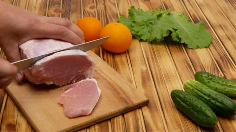 Raw meat cutting with a sharp knife on a cutting board, close up. Next to the Stock Footage 201884436
