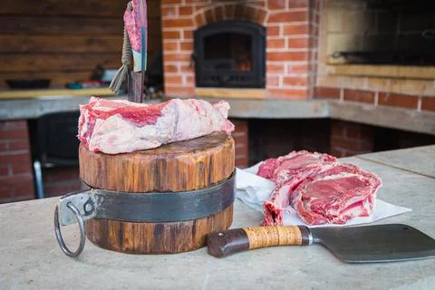 Raw meat on a deck, a knife stuck in the meat. Fresh meat on a cutting board. Stock Photos