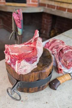 Raw meat on a deck, a knife stuck in the meat. Fresh meat on a cutting board. Stock Photos