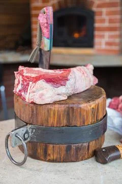 Raw meat on a deck, a knife stuck in the meat. Fresh meat on a cutting board. Stock Photos