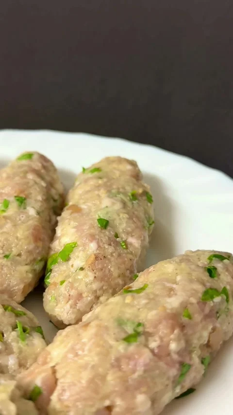 Raw meat kebabs with green herbs on white plate Vídeos de archivo 331974980