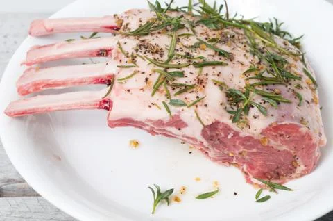 Raw meat, mutton, lamb rack marinated with fresh herbs Stock Photos