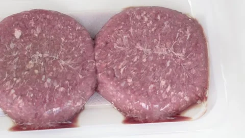 Raw meat patties in plastic container presented close view for retail and food Stock Footage 333773495