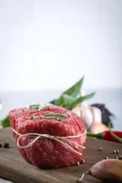 Raw meat. Raw beef steak on a cutting board with greens and spices. Stock Photos