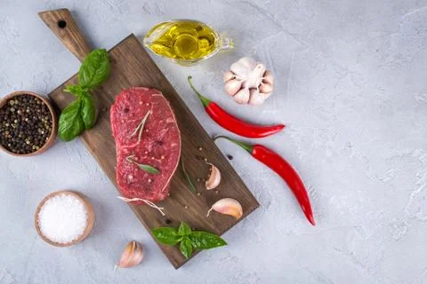Raw meat. Raw beef steak on a cutting board with greens and spices. Stock Photos