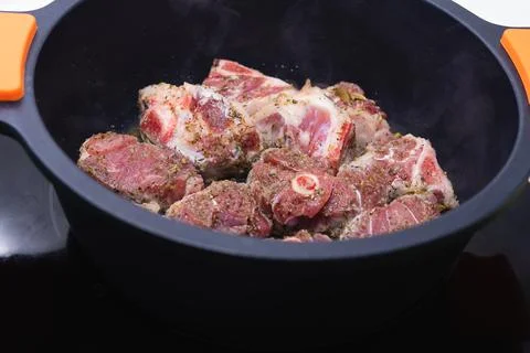 Raw meat ready to be cooked in a black casserole. Cooking concept. Stock Photos