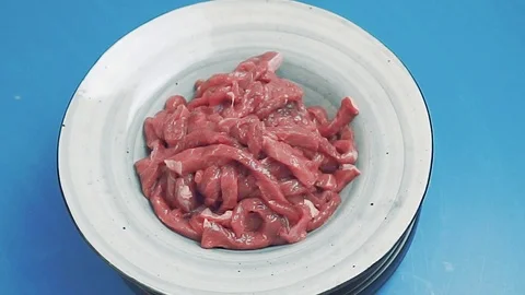 Raw meat rotating on blue background. Uncooked fresh meat cut into thin strips.  動画素材 110866000
