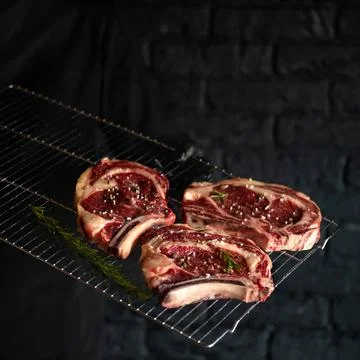 Raw meat steak on bone sprinkled with spices prepared for baking in oven. Meat Stock Photos