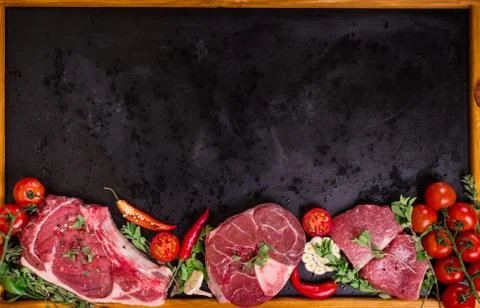 Raw meat steaks on a dark background ready to roasting Stock Photos
