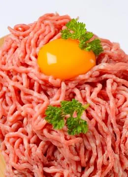 Raw meatball mixture with fried egg on top Stock Photos