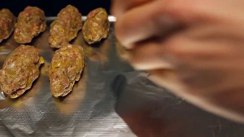 Raw meatballs being placed on baking tray Stock Footage 69949220