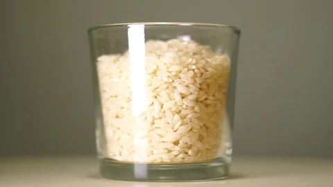 Raw medium-grain rice in transparent glass with white reflection Vídeo Stock 75241552