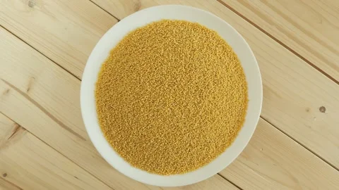 Raw millet grains rotating on a white plate Stock Footage 344604451