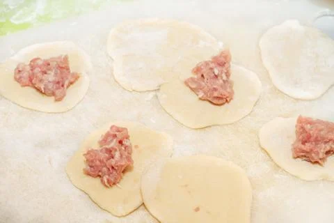 Raw minced meat prepared for modeling dumplings lies on the raw dough Stock Photos