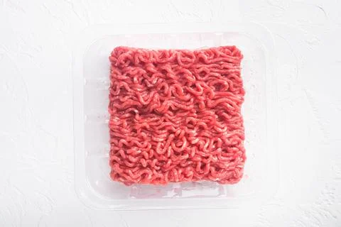 Raw Minced Meat in a transparent Plastic Container, on white stone background Stock Photos