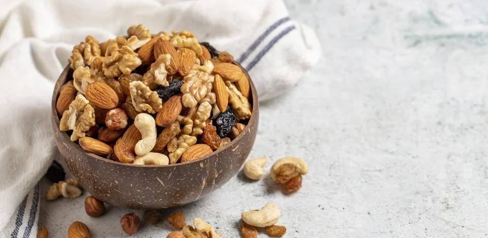 Raw mixed nuts on gray background. Walnuts, almonds, hazelnuts and raisins in Stock Photos