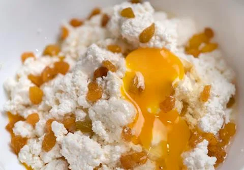 Raw mixture for making cheesecakes. Cottage cheese, raisins, egg yolk. Stock Photos