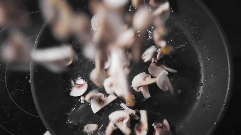 Raw mushrooms falls down on the frying pan, roasted champignones, vegetarian Stock Footage 76937442
