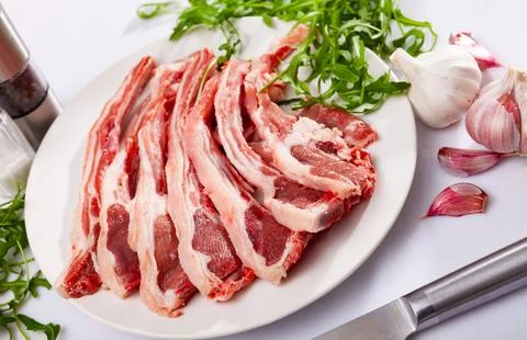 Raw mutton chops on plate with herbs and spices Фото