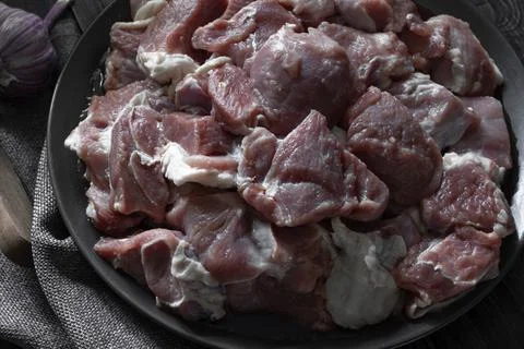 Raw mutton cut into medium pieces, lay on a plate, surrounded by garlic Foto stock