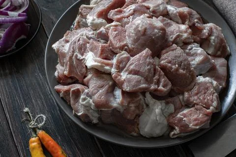 Raw mutton cut into medium pieces, lay on a plate, surrounded by red onions Foto stock
