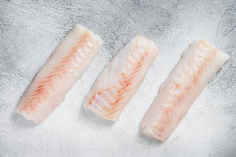 Raw Norwegian cod fish fillet on kitchen table. White background. Top view Stock Photos