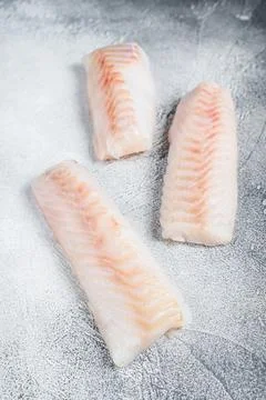 Raw Norwegian cod fish fillet on kitchen table. White background. Top view Stock Photos