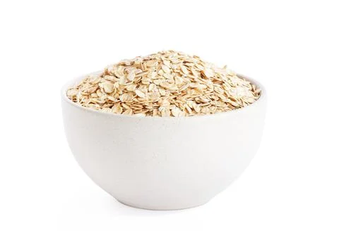 Raw oat flakes in light beige plate isolated on white background Stock Photos