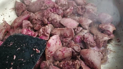 Raw organ meat cooking in steaming pan as dark spatula stirs and turns Stock Footage 346650357