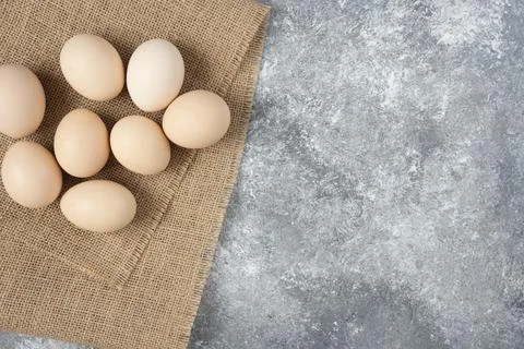 Raw organic eggs placed on top of sackcloth on marble background Stock Photos