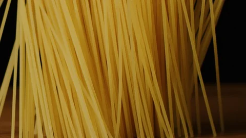 Raw pasta falls on wooden table macro shot Vídeo Stock 128480919