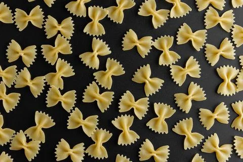 Raw pasta farfalle pattern on black background. Stock Photos