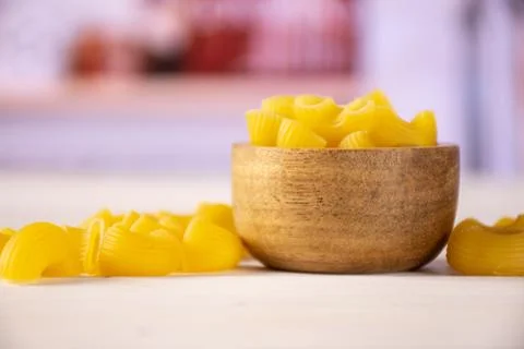 Raw pasta pipe rigate with kitchen behind Stock Photos