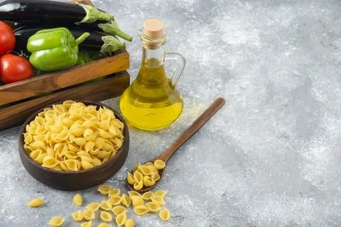Raw pasta in shell shaped with a glass bottle of oil and wooden box full of.. 库存照片