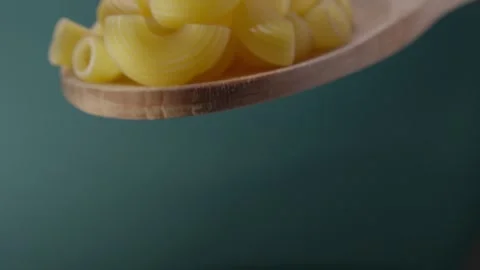 Raw Pasta Shells on Wooden Spoon Against Green Background Stock Footage 286241651
