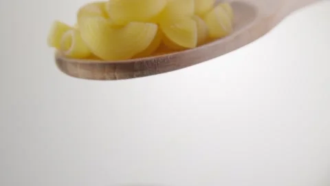 Raw Pasta Shells on Wooden Spoon Against Light Background Stock Footage 288829826